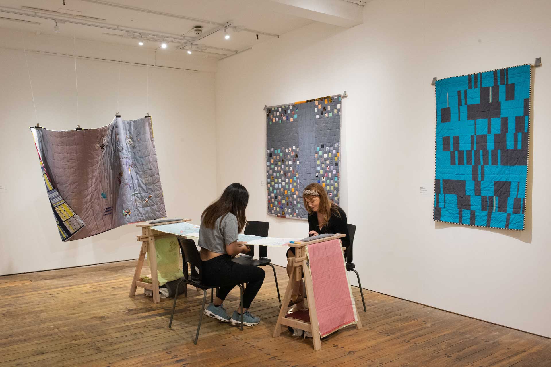 Two visitors taking part in the Quilting Together exhibition